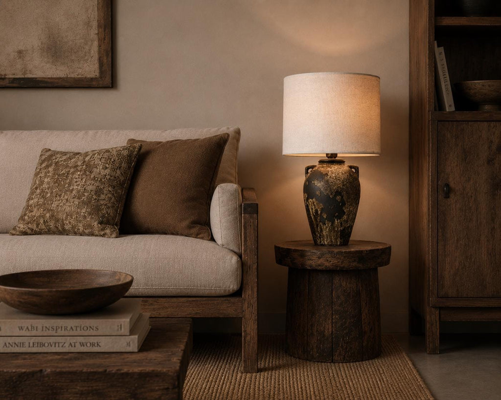 Handmade ceramic table lamp with ancient side handles, a wabi-sabi silhouette, and soft fabric shade casting a warm, timeless glow.