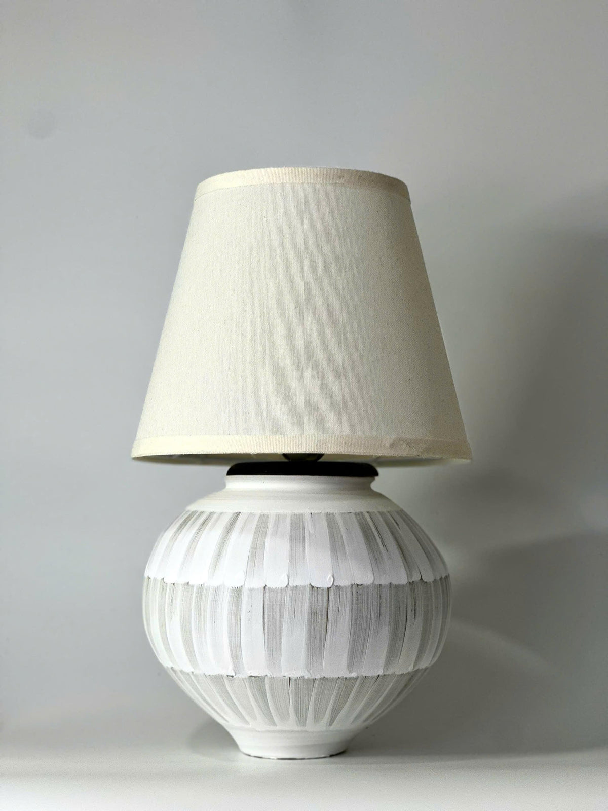 Handmade ceramic table lamp with a hand-painted ceramic body and soft fabric shade, casting a warm wabi-sabi glow.