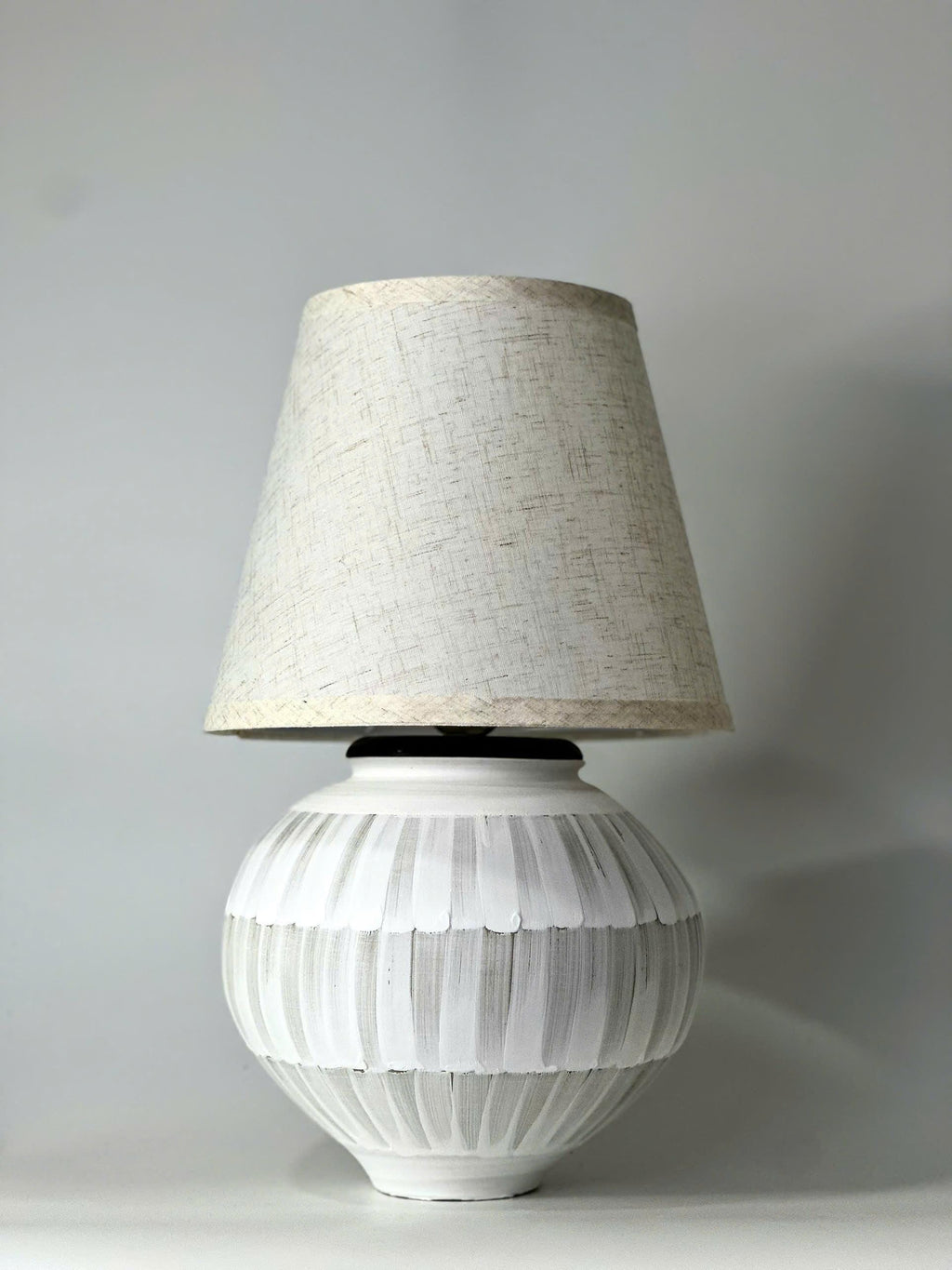 Handmade ceramic table lamp with a hand-painted ceramic body and soft fabric shade, casting a warm wabi-sabi glow.