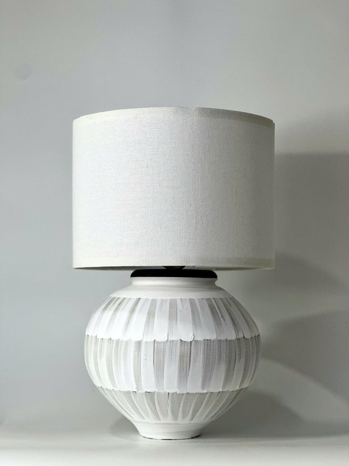 Handmade ceramic table lamp with a hand-painted ceramic body and soft fabric shade, casting a warm wabi-sabi glow.