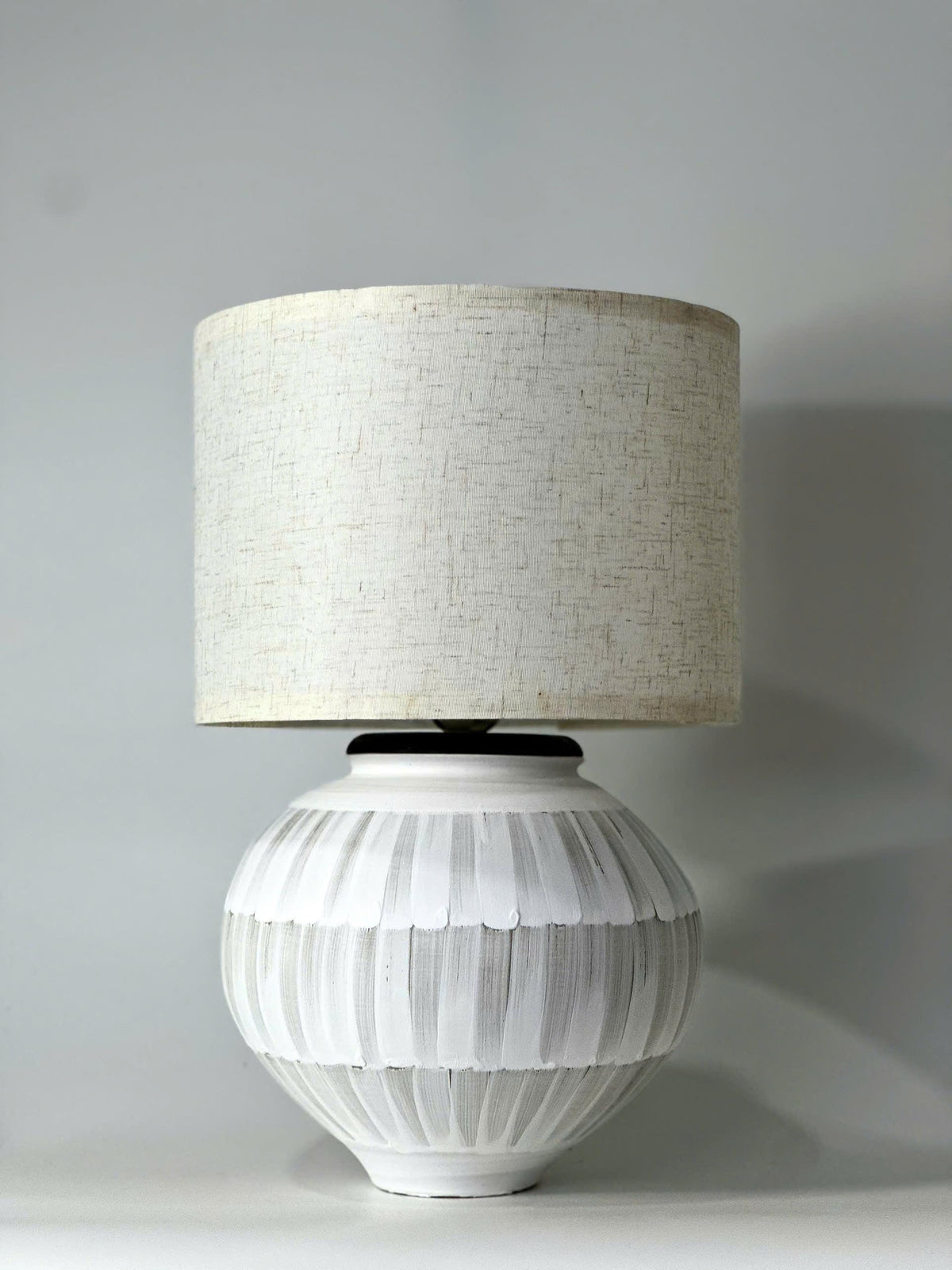 Handmade ceramic table lamp with a hand-painted ceramic body and soft fabric shade, casting a warm wabi-sabi glow.