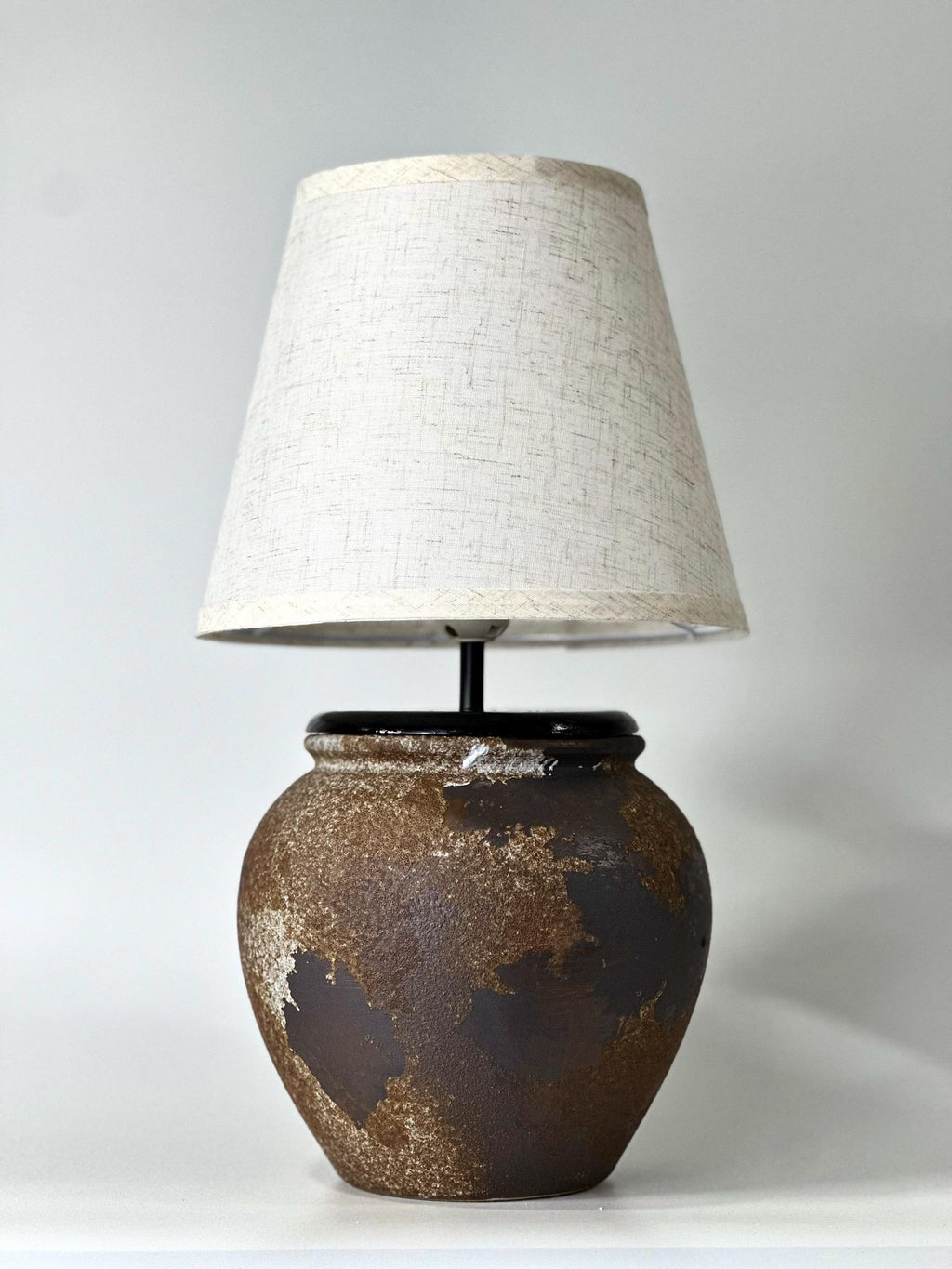 Handcrafted ceramic lamp with an aged earthen texture and timeless patina, paired with a warm linen shade for a soulful wabi-sabi glow.