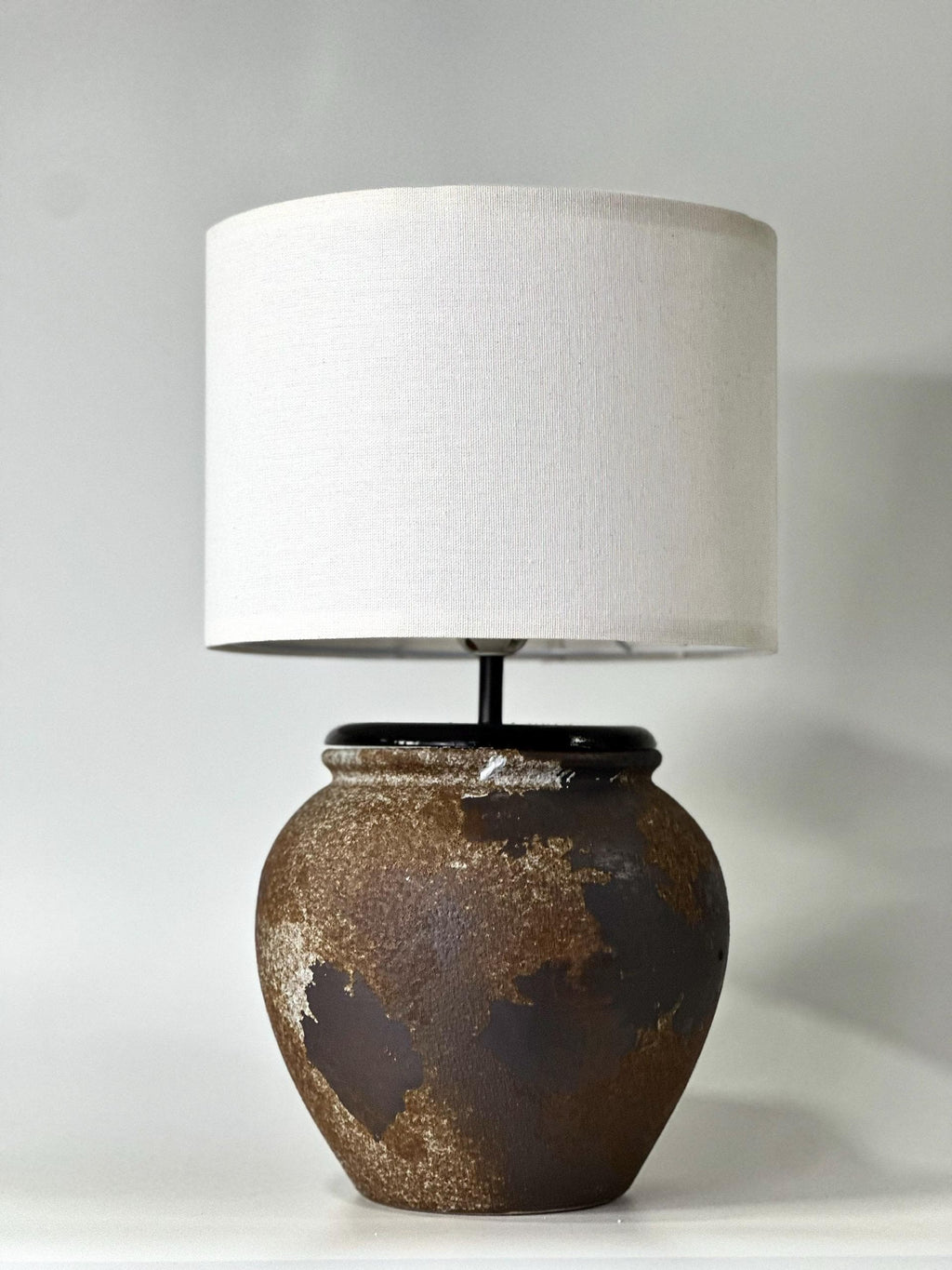 Handcrafted ceramic lamp with an aged earthen texture and timeless patina, paired with a warm linen shade for a soulful wabi-sabi glow.