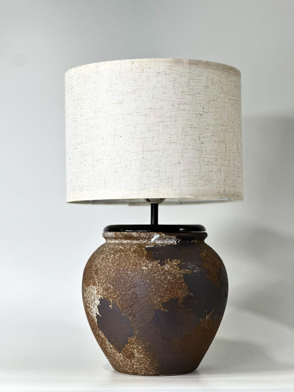 Handcrafted ceramic lamp with an aged earthen texture and timeless patina, paired with a warm linen shade for a soulful wabi-sabi glow.
