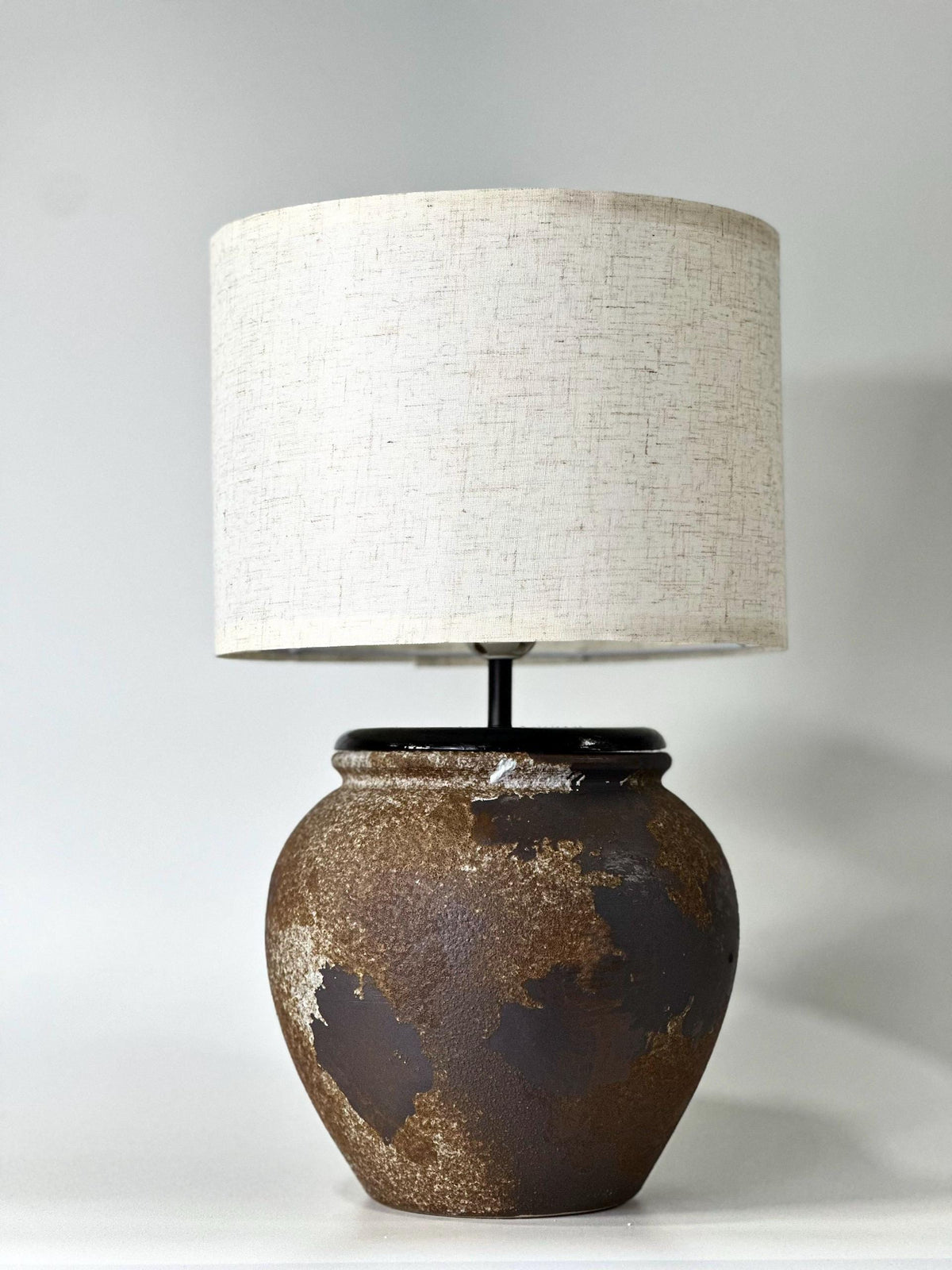 Handcrafted ceramic lamp with an aged earthen texture and timeless patina, paired with a warm linen shade for a soulful wabi-sabi glow.