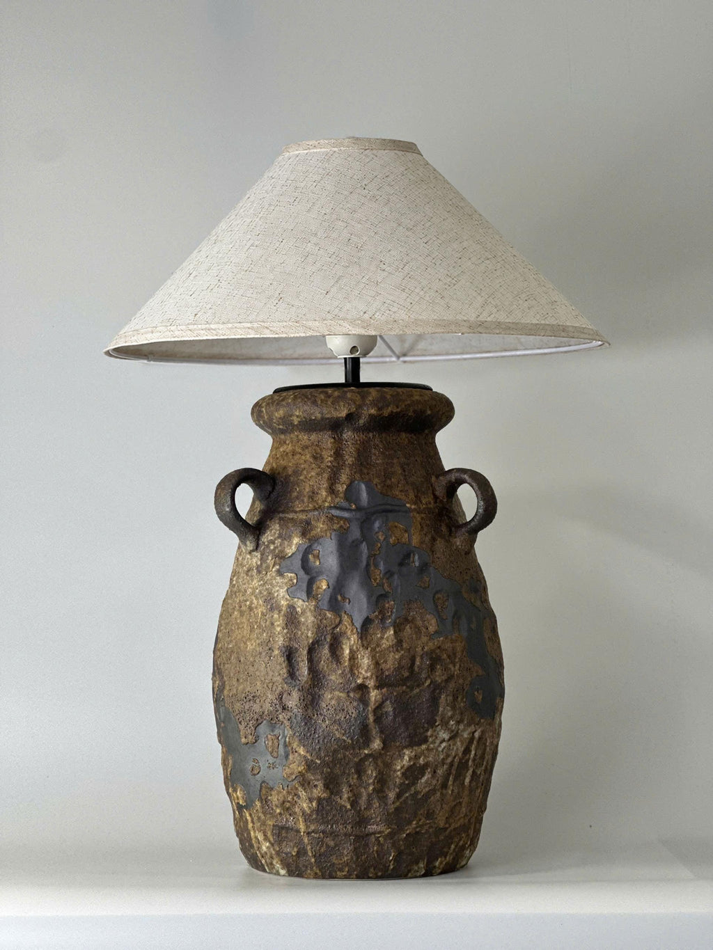 Handcrafted ceramic table lamp with rustic earthy textures, creating a warm, cozy glow for wabi-sabi, Japandi, and modern homes.