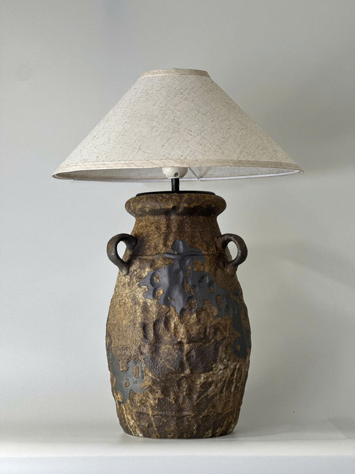 Handcrafted ceramic table lamp with rustic earthy textures, creating a warm, cozy glow for wabi-sabi, Japandi, and modern homes.