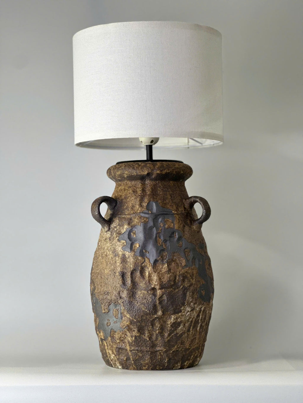 Handcrafted ceramic table lamp with rustic earthy textures, creating a warm, cozy glow for wabi-sabi, Japandi, and modern homes.